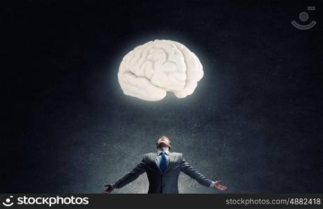 Great mental ability. Businessman with hands spread wide and human brain above his head