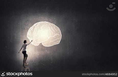 Great mind concept. Businesswoman standing on chair and reaching brain concept above