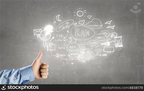 Great plan for success. Businessman hand showing thumb up to sketched plan on wall