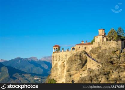 Greece. Clear summer day in Meteora. Arbor and rock monastery with red roofs against the backdrop of a mountain valley. Greek Rock Monastery and Gazebo and Mountains