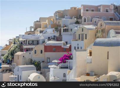 Greece. Summer sunny day in Santorini caldera. Balconies and colorful houses in Oia. Terraces with Balconies and Chairs on Santorini Caldera on a Sunny Summer Day