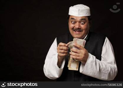 Greedy mature politician counting money over black background