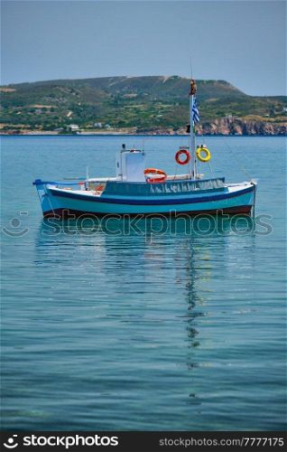Greek fishing boat moored in blue waters of Aegean sea in harbor of near Milos island, Greece. Greek fishing boat in Aegean sea near Milos island, Greece