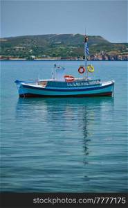 Greek fishing boat moored in blue waters of Aegean sea in harbor of near Milos island, Greece. Greek fishing boat in Aegean sea near Milos island, Greece
