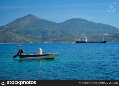 Greek fishing speed boat and cargo ship in the Aegean sea, Milos island, Greece. Greek fishing speed boat and cargo ship in the Aegean sea, Greece