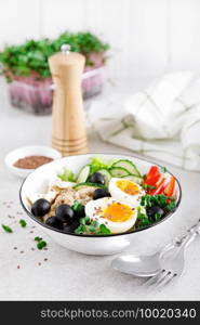 Greek inspired savory oatmeal with fresh cucumber, bell pepper, olives, lettuce, feta cheese, radish sprouts and soft-boiled egg for healthy breakfast