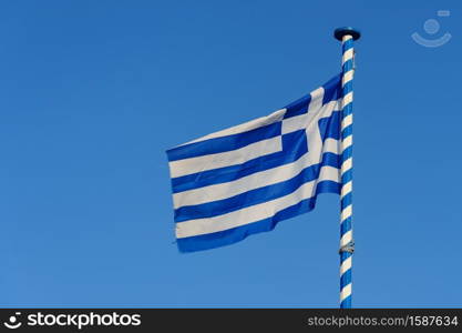 Greek national flag waving at blue sky background, Greece.