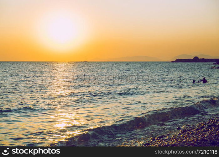 Greek Republic. Sunshine in sea and swimming people. In the distance mountains and sky. 17. Sep. 2019.