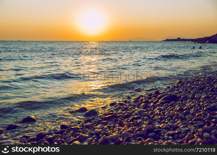 Greek Republic. Sunshine in sea and swimming people. In the distance mountains and sky. 17. Sep. 2019.