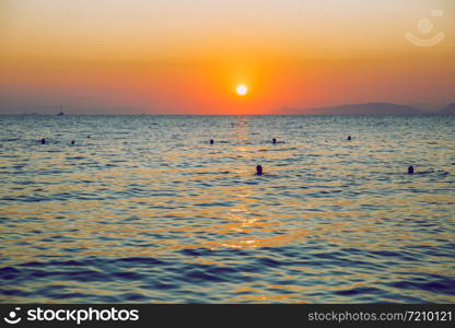 Greek Republic. Sunshine in sea and swimming people. In the distance mountains and sky. 17. Sep. 2019.