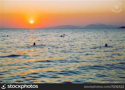 Greek Republic. Sunshine in sea and swimming people. In the distance mountains and sky. 17. Sep. 2019.