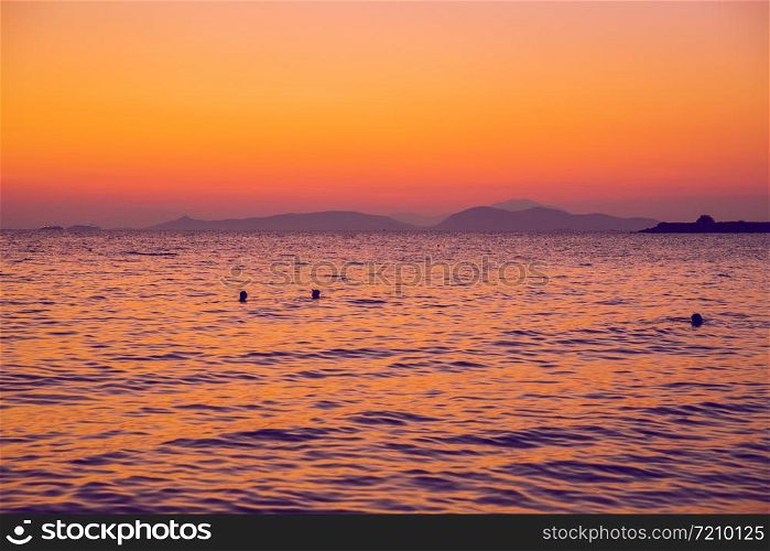 Greek Republic. Sunshine in sea and swimming people. In the distance mountains and sky. 17. Sep. 2019.
