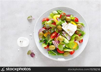 Greek salad. Fresh vegetable salad of cucumbers, tomatoes, olives, onion, bell pepper, feta cheese, lettuce and herbs and dressed with salt, pepper and olive oil. Horiatiki salad