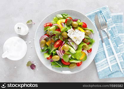 Greek salad. Fresh vegetable salad of cucumbers, tomatoes, olives, onion, bell pepper, feta cheese, lettuce and herbs and dressed with salt, pepper and olive oil. Horiatiki salad