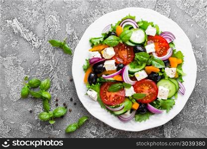 Greek salad. Fresh vegetable salad with tomato, onion, cucumbers, basil, pepper, olives, lettuce and feta cheese. Greek salad on plate