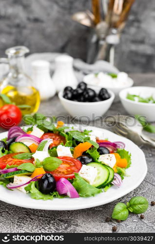 Greek salad. Fresh vegetable salad with tomato, onion, cucumbers, basil, pepper, olives, lettuce and feta cheese. Greek salad on plate