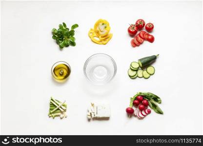 Greek salad ingredients and empty bowl in the middle on white tabletop. Flat lay of summer salad ingredients. Making of salad. Preparing healthy food.