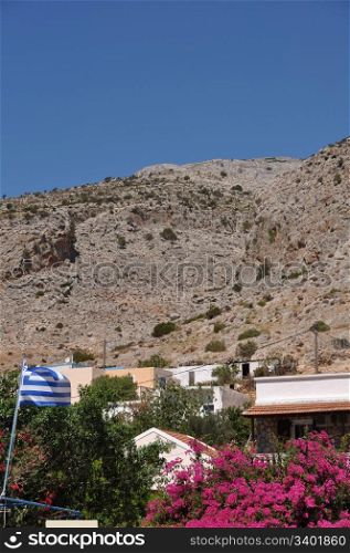 greek scene with national flag and bougainvillea in Kalymnos island port