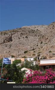 greek scene with national flag and bougainvillea in Kalymnos island port