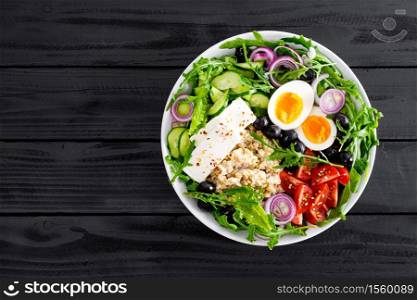 Greek style healthy breakfast bowl with oatmeal porridge and fresh vegetable salad of lettuce, arugula, olives, tomato, cucumber, feta cheese and boiled egg