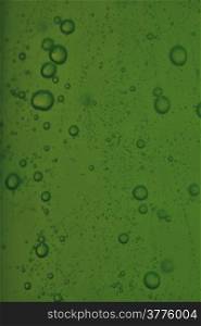 Green abstract blurred liquid background with soap bubbles