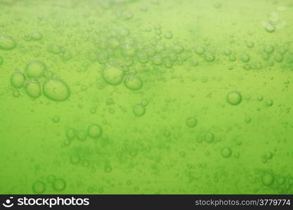 Green abstract blurred liquid background with soap bubbles