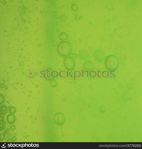 Green abstract blurred liquid background with soap bubbles. Square format