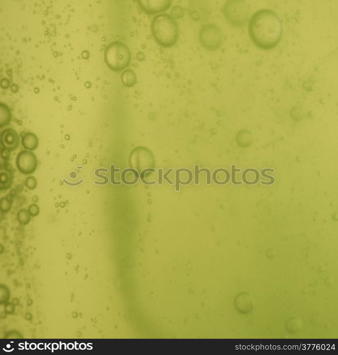 Green abstract blurred liquid background with soap bubbles. Square format