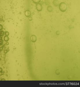 Green abstract blurred liquid background with soap bubbles. Square format