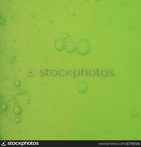 Green abstract blurred liquid background with soap bubbles. Square format