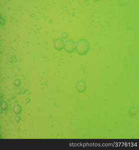 Green abstract blurred liquid background with soap bubbles. Square format