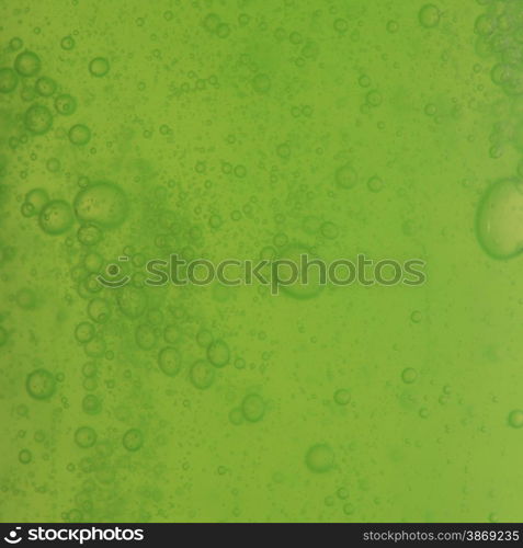 Green abstract blurred liquid background with soap bubbles. Square format