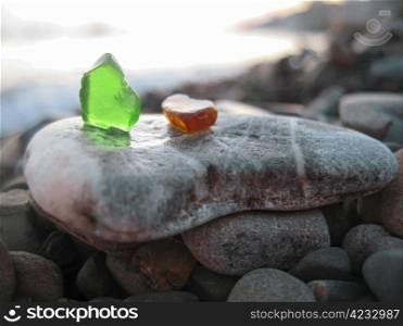 Green and orange glass laying on the sea shore