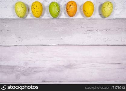 green and orange yellow easter eggs on a background of old wooden boards resembling old parquet. Easter concept.. green and orange yellow easter eggs on a background of old wooden boards resembling old parquet. Easter concept
