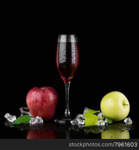 Green and red apple with a glass of champagne on black background