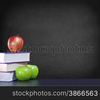 Green and red apples with books on black background.