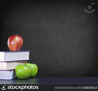 Green and red apples with books on black background.