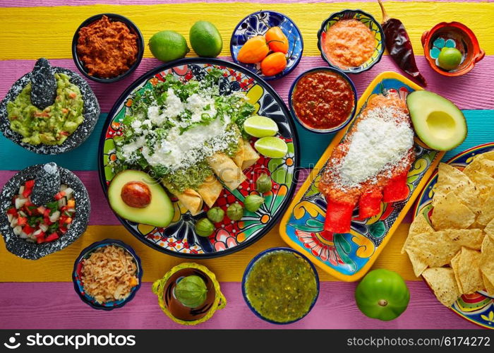 Green and red enchiladas with mexican sauces mix in colorful table