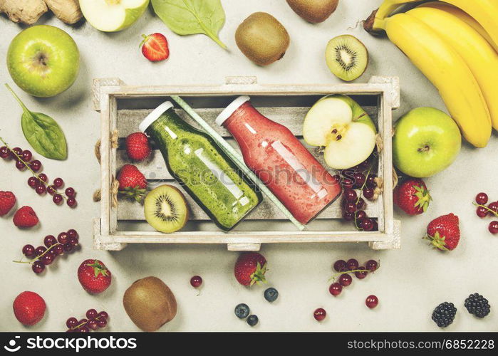 Green and red fresh juices or smoothies with fruit, greens, vegetables on grey background, top view, selective focus. Detox, dieting, clean eating, vegetarian, vegan, fitness, healthy lifestyle concept