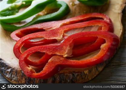 Green and red pepper slices on a cutting board of olive tree wood