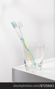 Green and yellow toothbrush in glass.