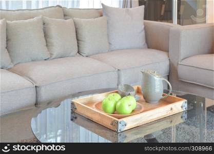 Green apple and ceramic tea cup in wooden tray on the center table at living room