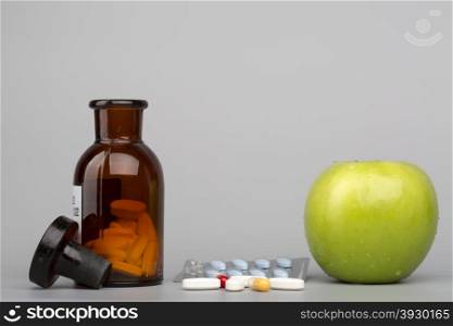 Green apple and colored pills with brown bottle . Green apple and colored pills and blister pack with brown bottle