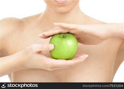 Green apple in hands against the bared female shoulders, isolated