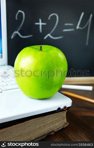 green apple on laptop ,old book and blackboard, selective focus