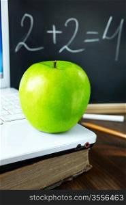 green apple on laptop ,old book and blackboard, selective focus