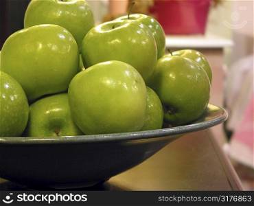 Green apples in a bowl on kitchen countertop