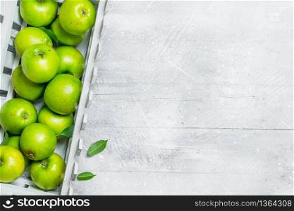 Green apples in a plastic box. On white rustic background.. Green apples in a plastic box.