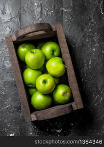 Green apples in a wooden box. On a dark wooden background.. Green apples in a wooden box.