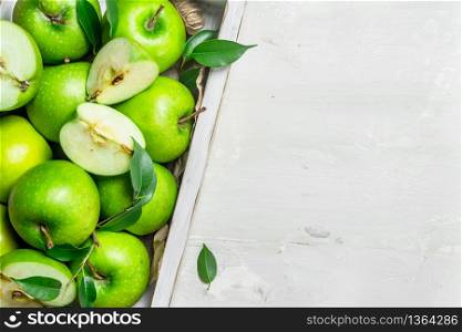 Green apples in a wooden tray. On white rustic background .. Green apples in a wooden tray.